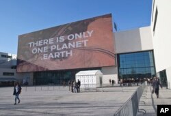Participants walk past the main entrance of the One Planet Summit, in Boulogne-Billancourt near Paris, France, Dec. 12, 2017.