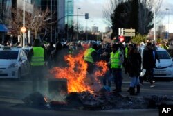 Sopir taksi berunjuk rasa dengan membakar kontainer sampah untuk memblokir akses ke pusat pameran perdagangan di Madrid, Spanyol, Rabu, 23 Januari 2019.