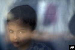 Migrant Petram Mehdi, 2, from Tehran, Iran, stands by the window of his family's shelter at the refugee camp of Ritsona about 86 kilometers (53 miles) north of Athens, Jan. 12, 2017.
