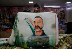 FILE - A salesman displays a sari, a traditional clothing worn by women, with a printed image of Indian Air Force pilot Abhinandan Varthaman, who was captured and later released by Pakistan, inside a sari manufacturing factory in Surat, India, March 8, 20