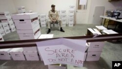 FILE - A security guard stands watch over ballots in a secured area during the write-in ballot count, Nov. 11, 2010, in Juneau, Alaska.