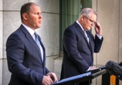 Perdana Menteri Australia Scott Morrison (kanan) bersama Menteri Keuangan Josh Frydenberd memberikan keterangan pers di Gedung Parlemen Australia di Canberra, 22 Maret 2020. (Foto: AFP)