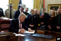 President Donald Trump signs the first veto of his presidency in the Oval Office of the White House, March 15, 2019, in Washington. Trump issued the veto to protect his emergency declaration for border wall funding.