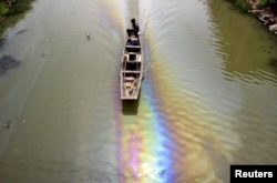 FILE - A man drives a boat along a river polluted by leaked fuel in Shaoxing, Zhejiang province, China, April 29, 2015.