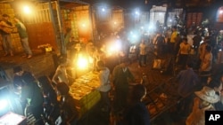 FILE - In this March 9, 2013 photo, porters unload boxes of Chinese fruits near traders at Long Bien wholesale market for fruits and vegetables in Hanoi, Vietnam.