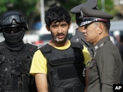 Police officers escort a key suspect in last month's Bangkok bombing, yellow shirt, identified by Thai police as Yusufu Mierili, also as Yusufu Mieraili, traveling on a Chinese passport, but his nationality remains unconfirmed, outside Hua Lamphong railwa