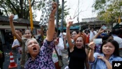 Voters hold their identification cards and the chains that held the gate of the polling station closed, as they demand the right to vote during general elections in Bangkok, Thailand, Feb. 2, 2014.