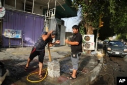 FILE - People cool themselves with water in central Baghdad, Iraq, July 16, 2015. The government declared Thursday an official holiday due to scorching temperatures.