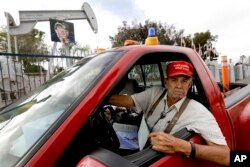 Ron Brindle poses for a photo in front of a portrait of Donald Trump hanging on his oil derrick in Huntington Beach, California, Jan. 10, 2017.