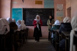 An Afghan girl reads in a classroom next to her teacher at Tajrobawai Girls High School, in Herat, Afghanistan, Nov. 25, 2021.