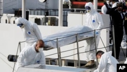 Italian Coast Guard officers carry body of a dead migrant off the ship Bruno Gregoretti, in Valletta's Grand Harbour, Monday, April 20 2015