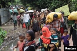 Rohingya refugees who arrived from Myanmar last night by boat, walk on the road of Shah Porir Dwip as they move to a refugee camp, in Teknaf, Bangladesh, October 7, 2017.