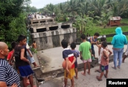 People look at the collapsed Anao-aon bridge after an earthquake hit Surigao city, southern Philippines, Feb. 11, 2017.