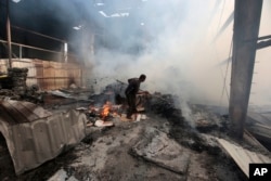 FILE - A worker looks for survivors under the rubble of a food factory hit by Saudi-led airstrikes in Sana'a, Yemen, Aug. 9, 2016.