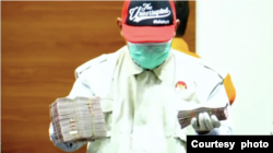 Petugas KPK menunjukkan barang bukti uang dalam Operasi Tangkap Tangan di Pengadilan Negeri Surabaya dalam konferensi pers pada 20 Januari 2022. (Foto: Tangkapan layar)