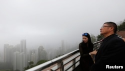 Mainland Chinese visitors look at the foggy skyline of Hong Kong island from the Peak in Hong Kong, Feb. 24, 2015.