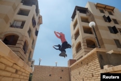 Para perempuan anggota Parkour Egypt atau "PKE" melatih keterampilan parkour di gedung-gedung di pinggiran Kairo, Mesir, 20 Juli 2018.