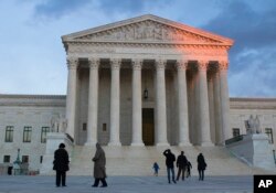 People stand on the plaza in front of the Supreme Court at sunset, Feb. 13, 2016, in Washington.