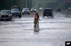 Cara Crawford, turns around after trying to ride her bike through high water to get to Sunday services at a nearby church, in the aftermath of Tropical Storm Harvey in Vidor, Texas, Sunday, Sept. 3, 2017.