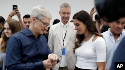 Apple CEO Tim Cook, left and soccer player Alex Morgan discuss the new Apple Watch 4 at the Steve Jobs Theater during an event to announce new products Wednesday, Sept. 12, 2018, in Cupertino, Calif. (AP Photo/Marcio Jose Sanchez)