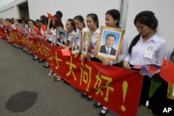 File photo - Cambodian students holding a welcome banner and photos of Chinese President Xi Jinping at Phnom Penh International Airport in Phnom Penh, Cambodia, Thursday, Oct. 13, 2016.