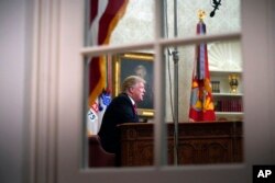 FILE - As seen from a window outside the Oval Office, President Donald Trump gives a prime-time address about border security, at the White House in Washington, Jan. 8, 2018.