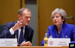FILE - British Prime Minister Theresa May and European Council President Donald Tusk attend a round table meeting at an EU summit in Brussels, Nov. 25, 2018.