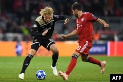 Pemain depan Ajax, Kasper Dolberg (kiri) dan gelandang Bayern Munich Javier Martinez berebut bola dalam laga Grup E Liga UEFA Champions antara Bayern Munich vs Ajax Amsterdam di Munich, 2 Oktober 20