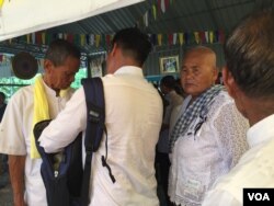 ឈរ​នៅ​បន្ទាប់​ពី​បុរស​ម្នាក់​ពី​ស្តាំដៃ​ គឺ​អ្នកស្រី​ ភោគ​ សេ ម្តាយ​បង្កើត​លោក​ កែម ឡី​ក្នុង​ពិធី​បុណ្យ​រំឭក​ខួប​មួយ​ឆ្នាំ​នៃ​ការ​ស្លាប់​របស់​លោក​ កែម ឡី ដែល​បាន​ធ្វើ​ឡើង​កាលពី​ថ្ងៃ​ ទី​ ៩​ ខែកក្កដា​ ឆ្នាំ​ ២០១៧​ នៅ​ខេត្តតាកែវ។ (ហ៊ុល រស្មី/VOA)