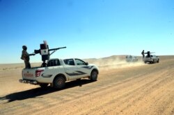 FILE - Forces loyal to Syria's President Bashar al-Assad ride on pick-up trucks mounted with weapons in the Badia, in the southeast Syrian desert, in this handout picture provided by SANA , June 13, 2017.