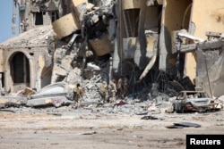 Libyan forces allied with the U.N.-backed government walk through a destroyed building during a battle with Islamic State militants in Sirte, Libya, Oct. 2, 2016.