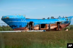 FILE - The wrecked fishing boat that capsized and sunk on April 18, 2015, off the coast of Libya, lies outside a NATO base in the Sicilian town of Mellili, Italy, Oct. 8, 2016.