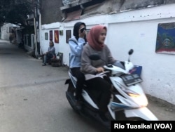 Pengendara motor melewati Gang Citra lokasi pameran 40-an lukisan Jitno Slamet, di kawasan Cicendo, Bandung, Kamis, 23 Agustus 2018. (Foto: Rio Tuasikal/VOA)