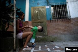 Veruska Torres plays with her son on the outskirts of Caracas, Venezuela, October 11, 2017. He is wearing a new t-shirt bought with prize money won on "Los Animalitos" (or the Little Animals) betting game.