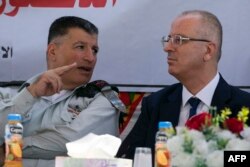 FILE - Palestinian prime minister Rami Hamdallah, right, sits next to Major General Yoav Mordechai, head of COGAT, the Israeli defense ministry agency responsible for civilian affairs in the Palestinian territories, as they attend a ceremony in Jalamah, near the northern West Bank city of Jenin, July 10, 2017.