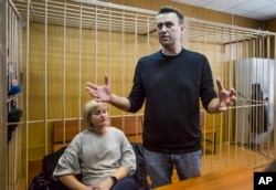 Russian opposition leader Alexei Navalny gestures while speaking, as his lawyer Olga Mikhailova listens, in court in Moscow, Russia, March 27, 2017.
