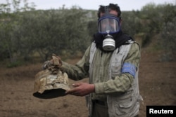 A Civil Defense member carries a damaged canister in Ibleen village from what activists said was a chlorine gas attack, on Kansafra, Ibleen and Josef villages in Syria, May 3, 2015.