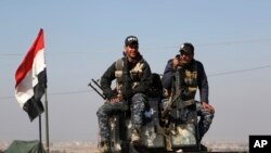 Two policemen sit atop of their armored vehicle as Iraqi federal police deploy after regaining control of the town of Abu Saif, west of Mosul, Iraq, Feb. 22, 2017.