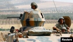 Turkish soldiers on an armoured personnel carrier escort a military convoy on a main road in Karkamis on the Turkish-Syrian border in the southeastern Gaziantep province, Turkey, Aug. 26, 2016.