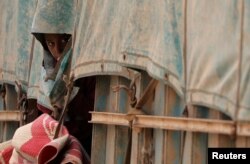 A boy looks out from beneath a truck tarp near the village of Baghuz, in Deir el-Zour province, Syria, March 7, 2019.