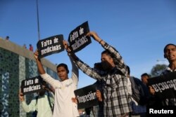 FILE - Opponents of the Madura administration hold placards that read "Shortage of medicines" during a protest in Caracas, Venezuela, March 30, 2017.