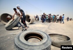 Iraqi protesters move tires and concrete blocks to block the road during a protest in south of Basra, Iraq July 16, 2018.