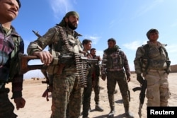 Syria Democratic Forces fighters carry their weapons in a village on the outskirts of al-Shadadi town, Hasaka countryside, Syria, Feb. 19, 2016.