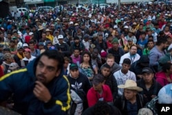 Central American migrants, part of one of the caravans hoping to reach the U.S. border, listen to a coordinator during the early-morning hours in Sayula de Aleman, Veracruz state, Mexico, Nov. 3, 2018.