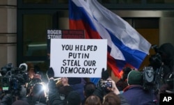 Former campaign adviser for President Donald Trump, Roger Stone, is surrounded by protesters and supporters with signs and flags of Russia, and media, as he arrives at federal court in Washington, Tuesday, Jan. 29, 2019.