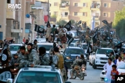 FILE - Fighters from the Islamic State parade through Raqqa, north Syria, in this undated file image posted June 30, 2014, by the Raqqa Media Center of the Islamic State group. Due to the decline in areas under the terror group's control and plunging revenues, IS reportedly is struggling to pay its foreign fighters' wages.