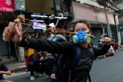 A demonstrator uses a slingshot during clashes with police at a protest against what they call the government's failure in handling the coronavirus disease (COVID-19) outbreak, in Bangkok, Thailand, August 7, 2021.