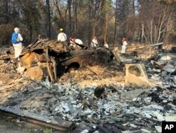 Volunteer members of an El Dorado County search and rescue team search the ruins of a home and vehicle, looking for human remains, in Paradise, Calif., Nov. 18, 2018, following a Northern California wildfire.