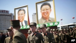 North Korean soldiers walk in the Ryomyong residential area, a collection of more than a dozen apartment buildings, after attending its official opening ceremony, while portraits of the late leaders Kim Il Sung and Kim Jong Il are seen on April 13, 2017.