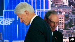 Former U.S. President Bill Clinton, left, passes former New York Mayor Michael Bloomberg after he was introduced as a speaker at the Bloomberg Global Business Forum, Sept. 20, 2017, in New York.